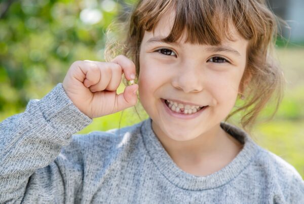 child holding a tooth that fell out of their mouth