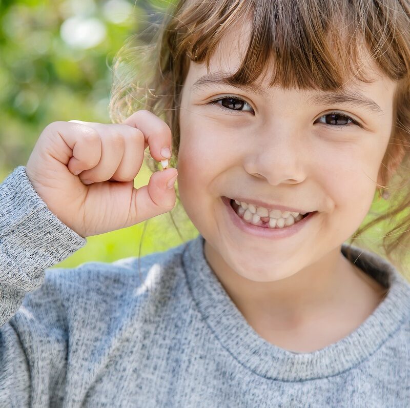 child holding a tooth that fell out of their mouth